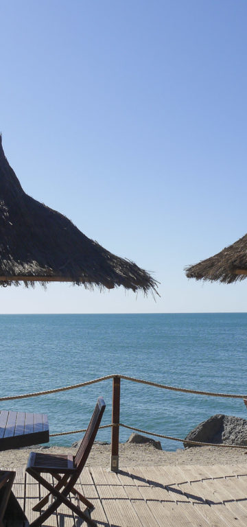 Camping Californie Plage - Galerie photo - Tables avec parasols sur la terrasse en bord de mer