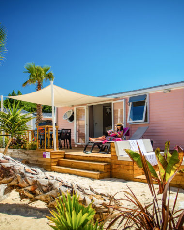 Camping Californie Plage - Locations - Hébergement avec terrasse semi couverte entouré de palmiers